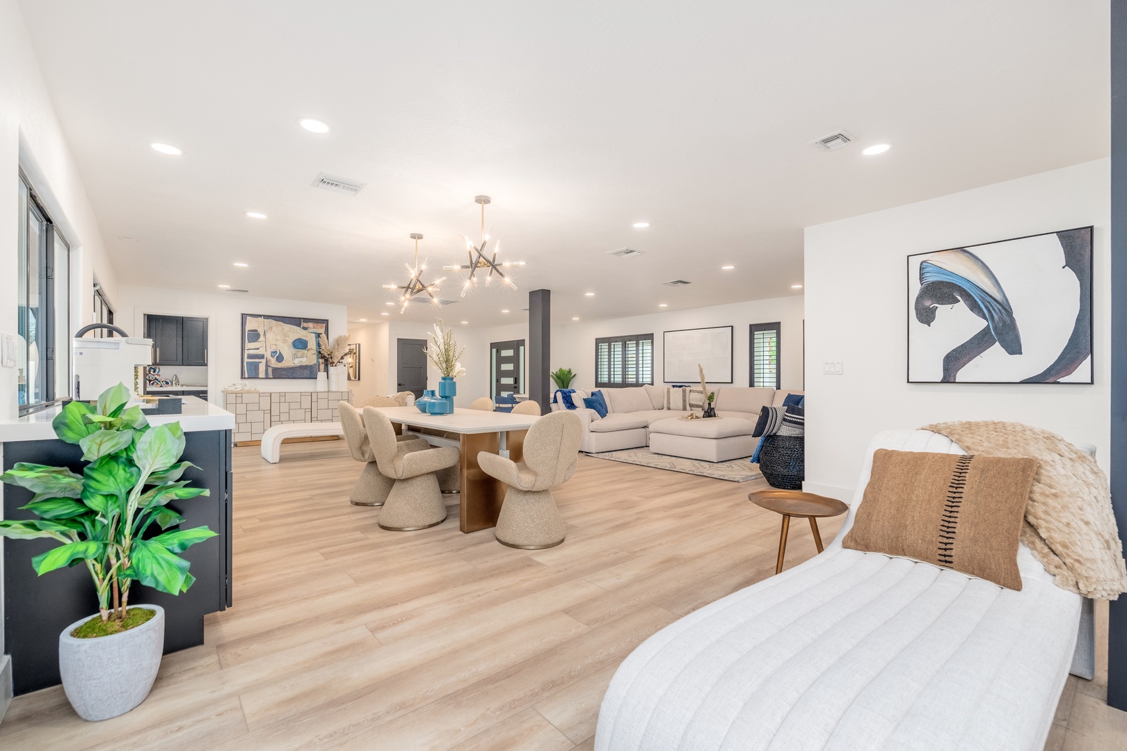 Unwind in your expansive open-concept living area, where modern design meets comfort with stylish seating, chic artwork, and warm natural light pouring through tall windows.