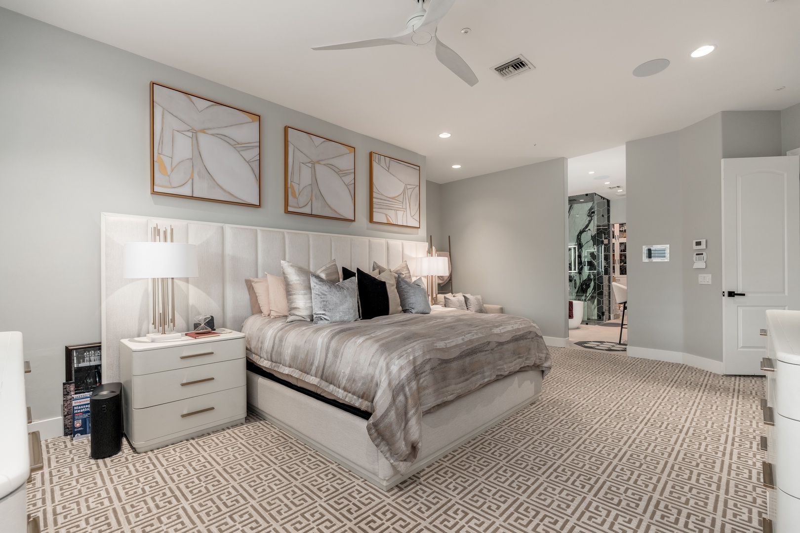 Sink into the plush king bed under soft neutrals and modern art, where a ceiling fan and bright lighting create your perfect sanctuary.