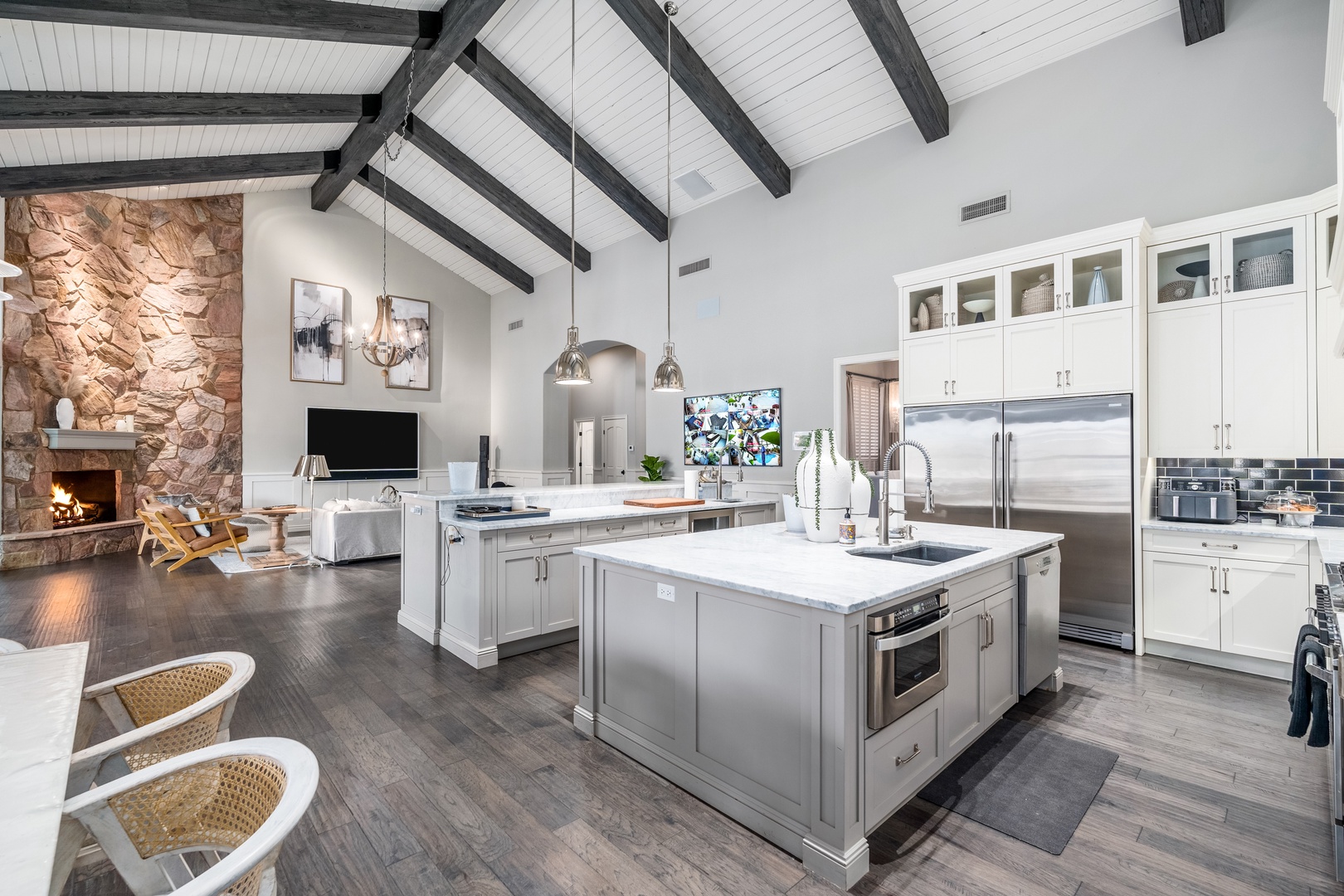 Gather in this soaring great room where vaulted beams frame your culinary adventures. The chef's kitchen flows into a cozy living space with a crackling stone fireplace, perfect for memorable evenings.