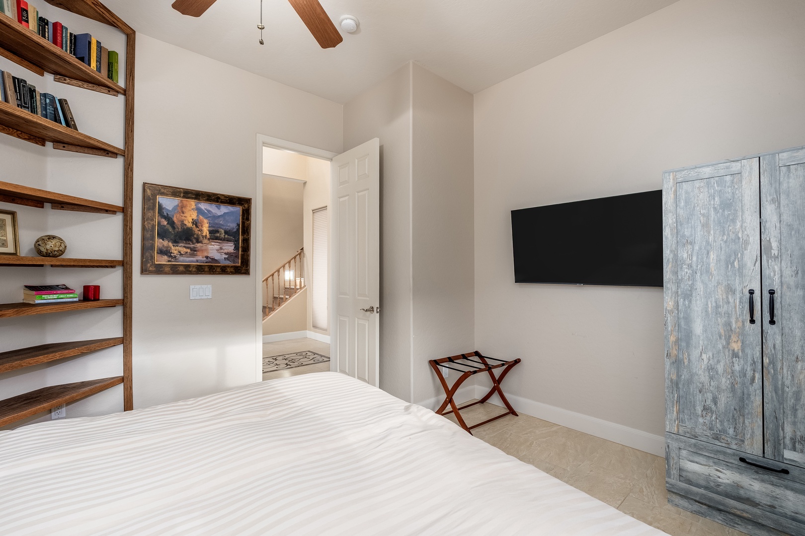 Your bright, serene bedroom features exposed beam ceilings, a wall-mounted TV, and a charming rustic armoire, with open shelving for your books and treasures.
