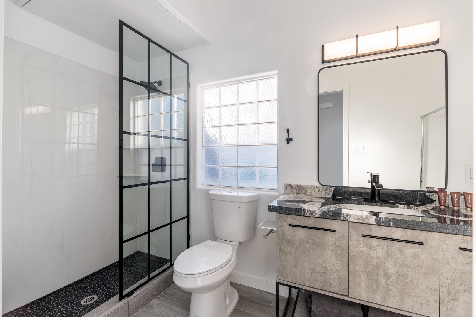 Refresh in your modern bathroom featuring a sleek walk-in shower, elegant vanity with stone countertops, and abundant natural light to start your day right.