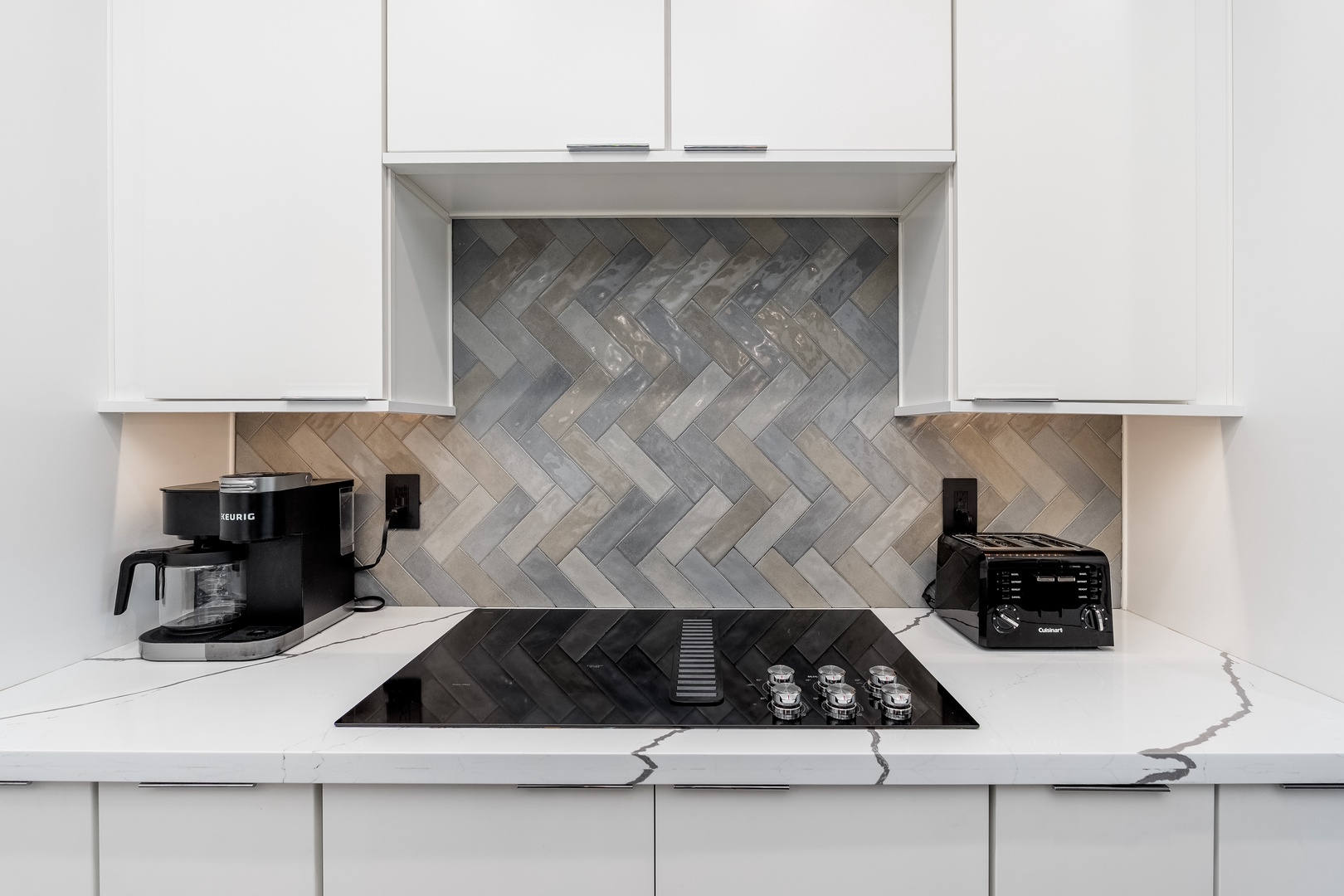 Your modern kitchen is ready for your culinary adventures, with a sleek cooktop, quality appliances, and stunning herringbone tile that adds warmth and character to every meal.