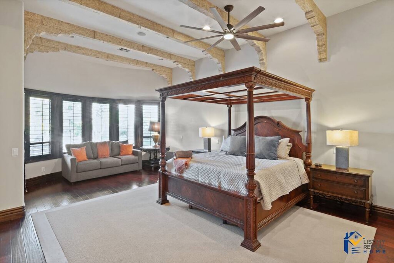 Unwind in your elegant master suite with soaring beamed ceilings, a majestic four-poster bed, and cozy seating nook by windows.