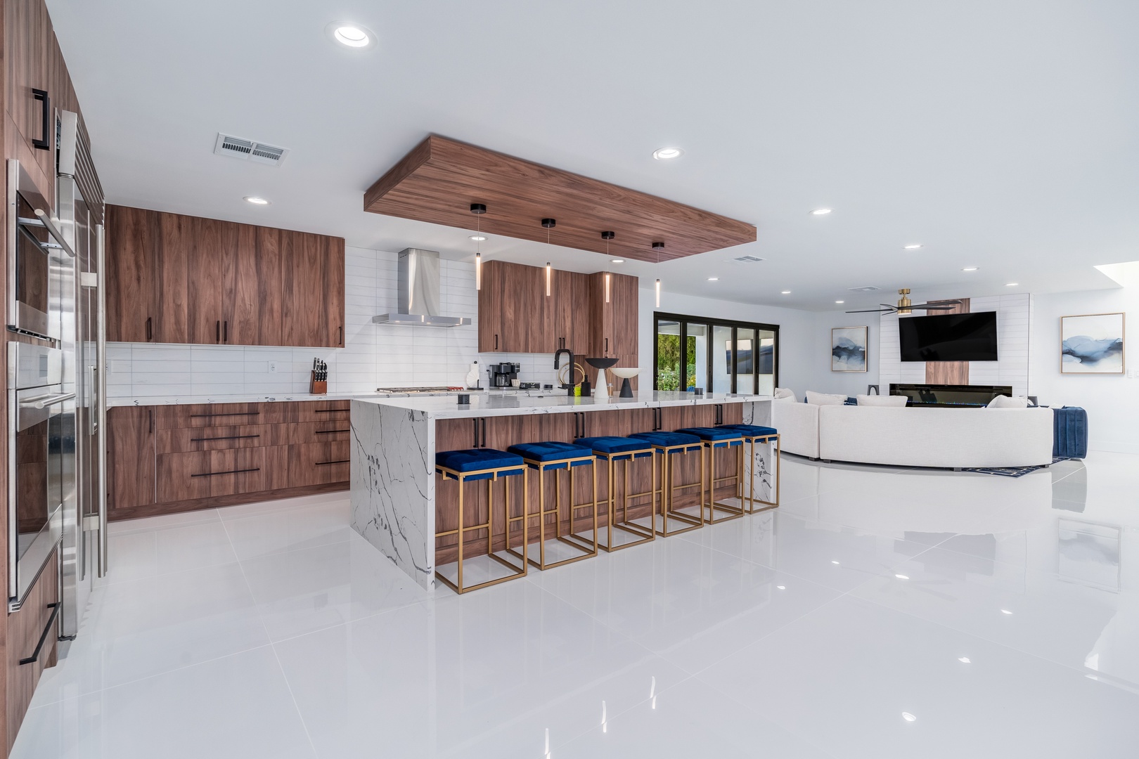You'll love gathering in this bright, open-concept space where a chef's kitchen flows seamlessly into the living area, featuring a stunning waterfall-edge island with chic bar seating and elegant wood finishes throughout.