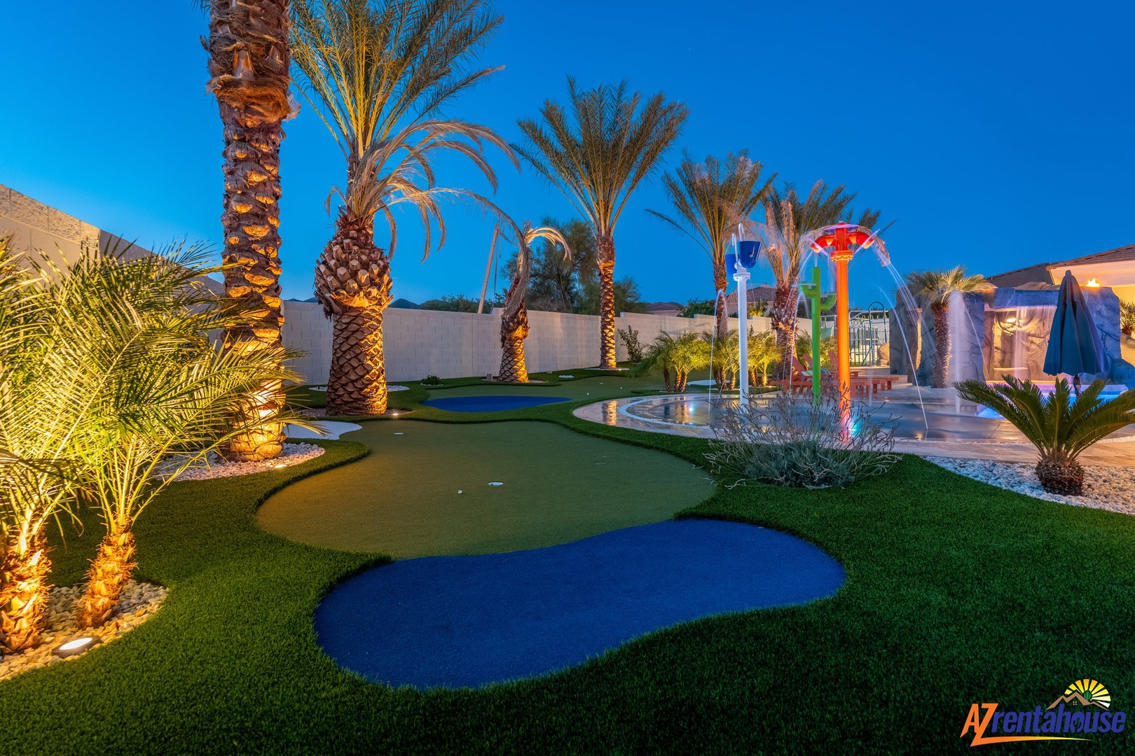 Enjoy your own private resort-style backyard with a putting green, colorful fountain, and tropical palms under the evening lights.