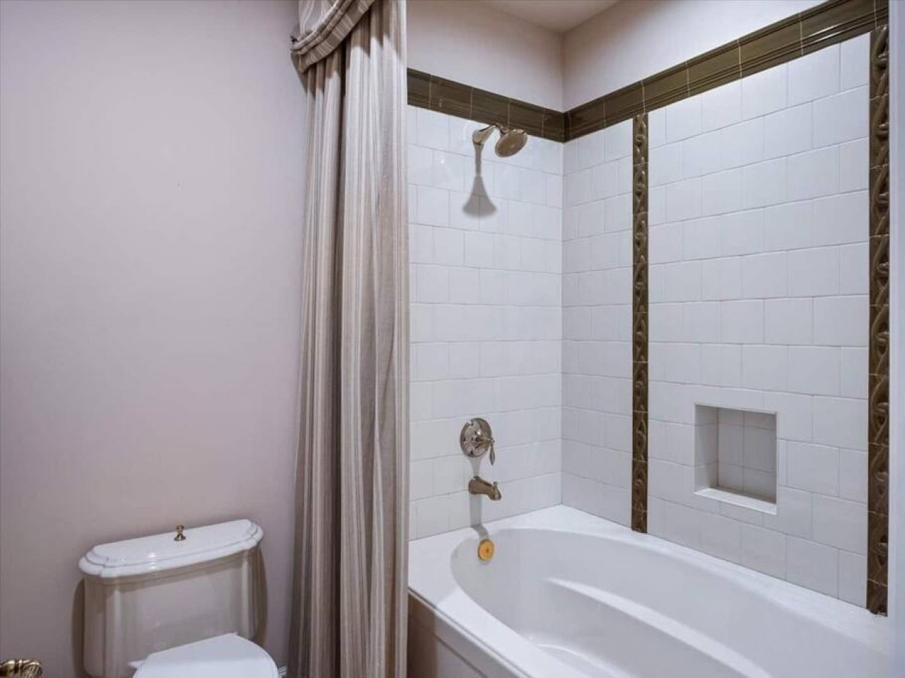 Your private bathroom features a sparkling tub-shower combo with modern fixtures and crisp white tile. A built-in niche offers convenient storage for your toiletries.