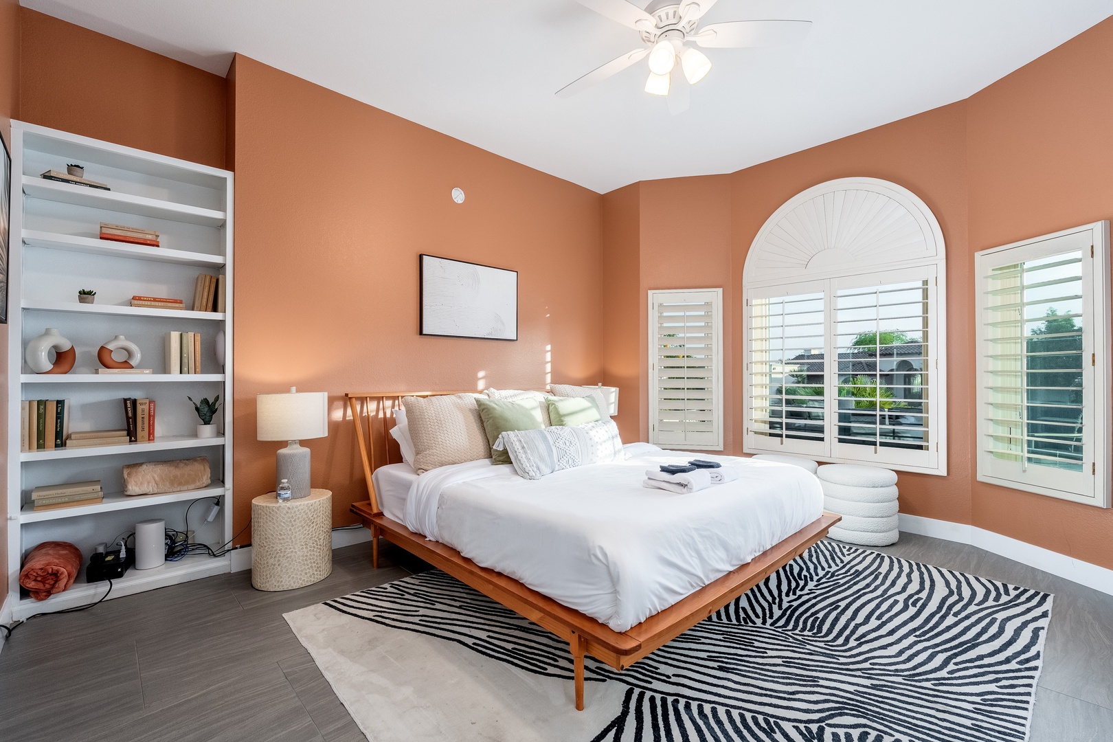 Sink into plush bedding in your private retreat, where warm terracotta walls and natural light create a tranquil escape. The bookshelf invites quiet moments, while ceiling fans keep you cool.