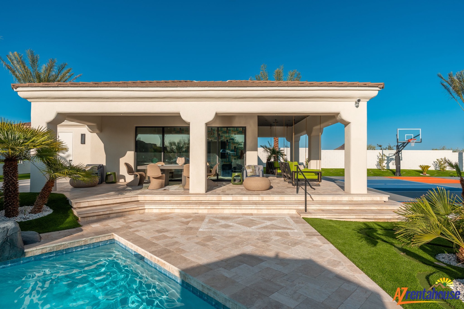 Modern villa with covered terrace, private pool, and tropical landscaping under clear blue skies.