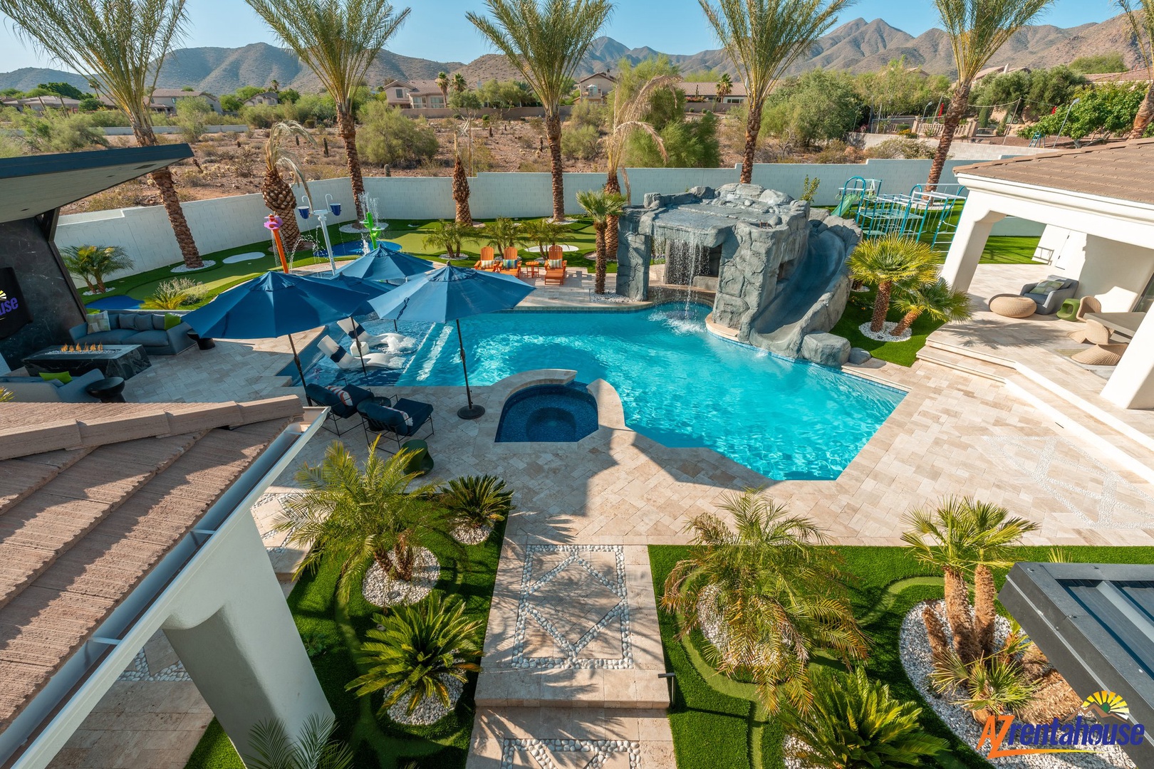 Stunning desert oasis featuring a sparkling pool with waterfall, lush palm trees, and mountain views creating your perfect vacation escape.