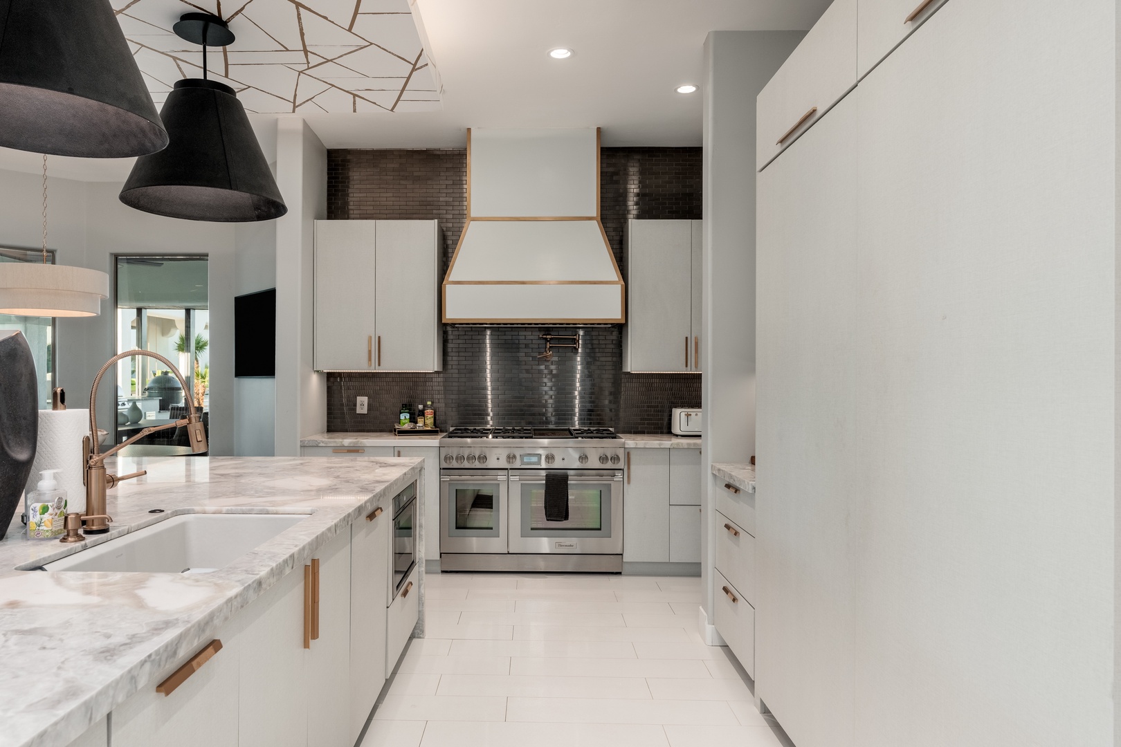 Your gourmet kitchen awaits with sleek white cabinetry, marble counters, and professional-grade appliances—perfect for preparing memorable meals during your stay.