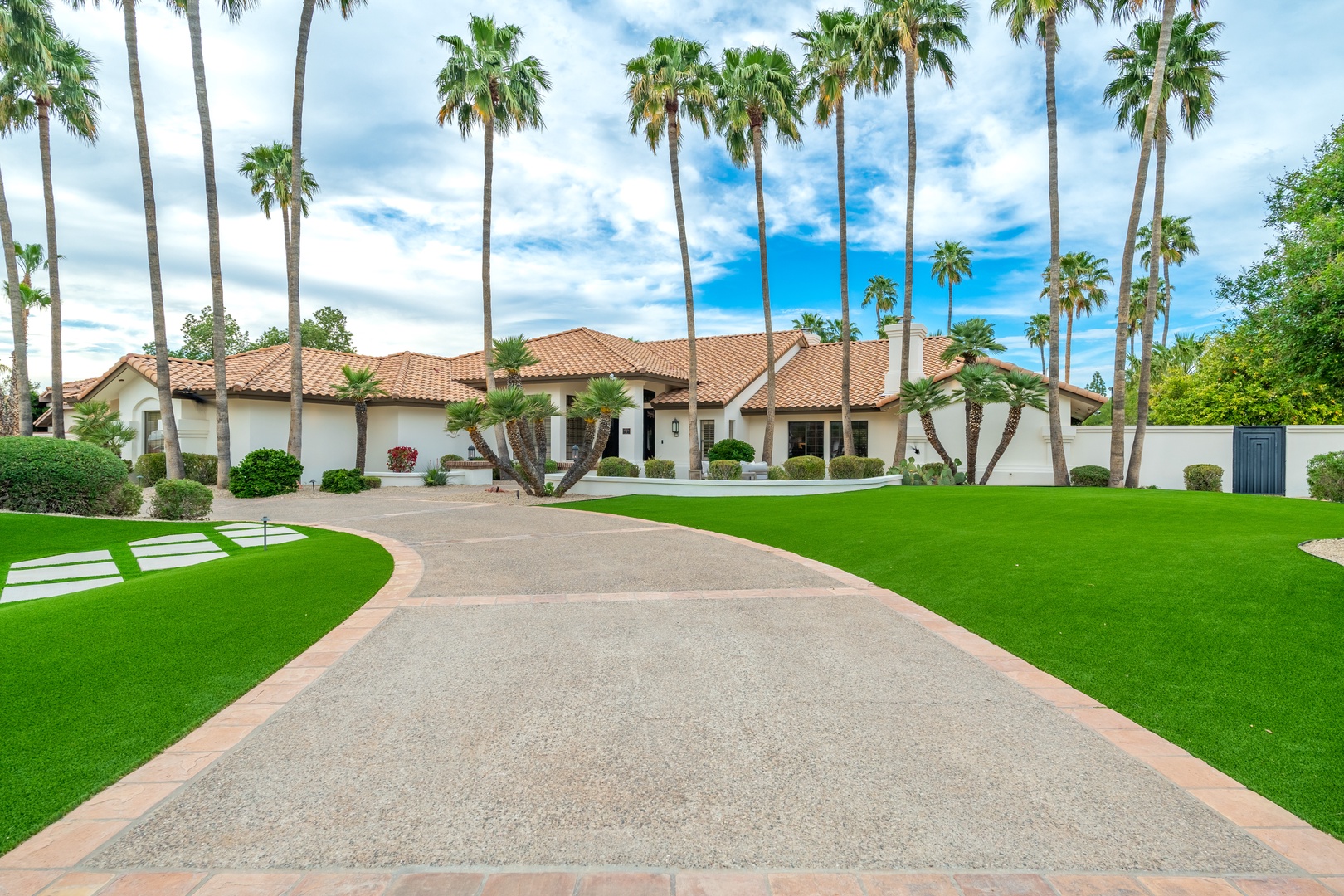 A sprawling Mediterranean-style estate framed by majestic palm trees and manicured grounds, offering a private desert oasis retreat.