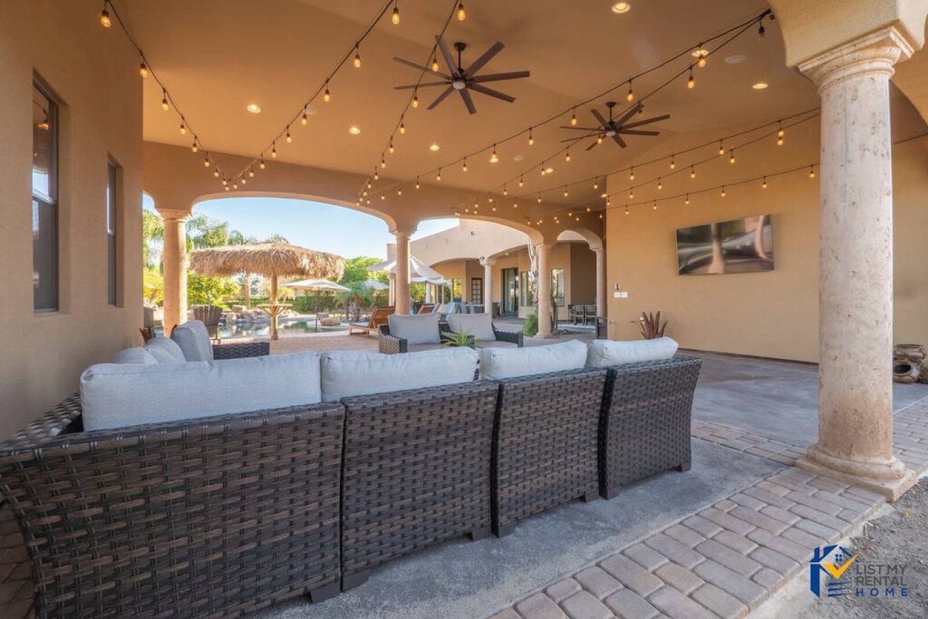 Your elegant covered patio offers plush seating under twinkling string lights, perfect for relaxing evenings with garden views.