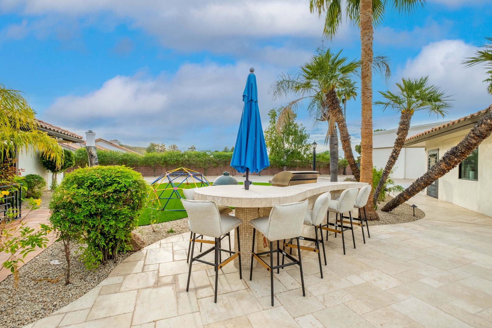 Gather around this outdoor dining area framed by swaying palms and lush greenery. Your ideal spot for morning coffee, afternoon cocktails, or sunset dinners under the desert sky.