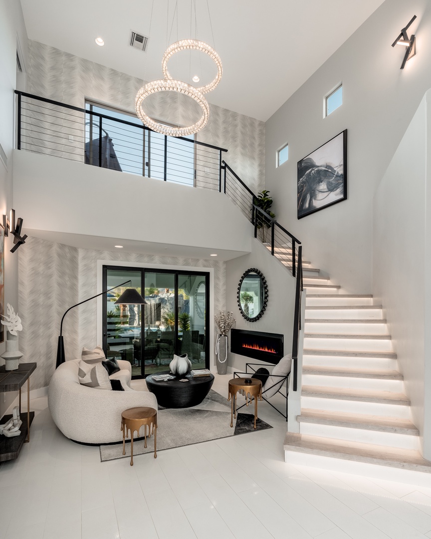 Sink into plush seating beneath soaring ceilings and statement chandeliers. Your elegant retreat features a cozy fireplace, chic décor, and seamless access to outdoor living.