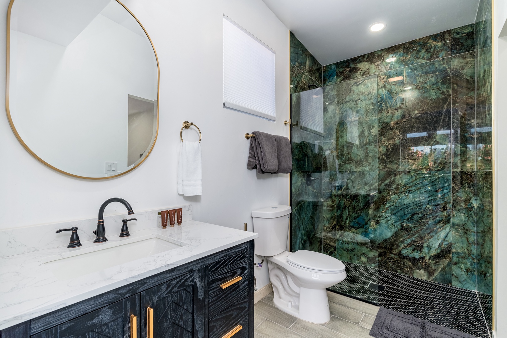 Step into your spa-like retreat with its dramatic emerald marble shower, elegant fixtures, and fresh towels awaiting you after a long day.
