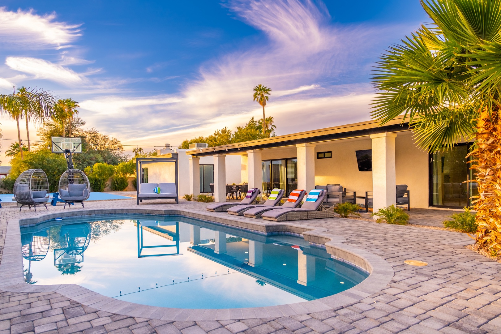 Stunning desert oasis retreat featuring a sparkling pool, modern architecture, and swaying palms beneath golden-hour skies—your perfect escape awaits.