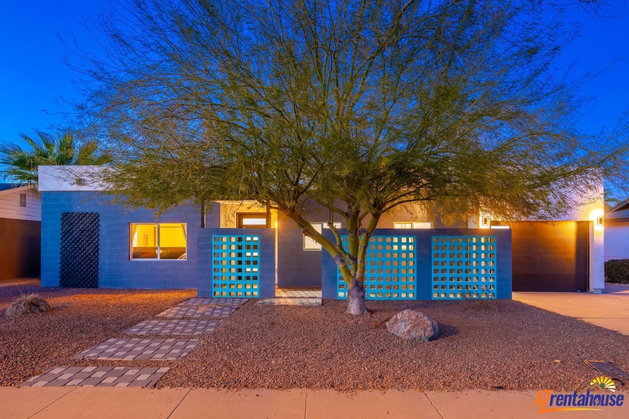 Modern desert home with stunning blue facade and warm lighting creates a striking architectural presence in the evening.