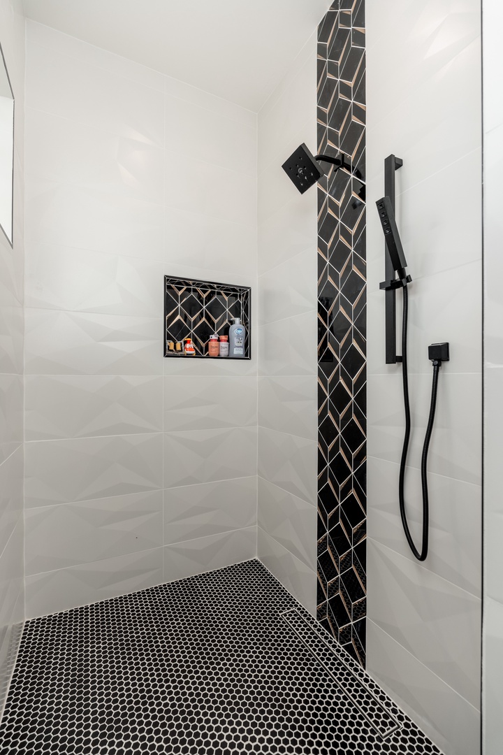 Step into your beautifully tiled walk-in shower, where elegant chevron accents and a built-in niche for your toiletries combine modern design with everyday convenience.