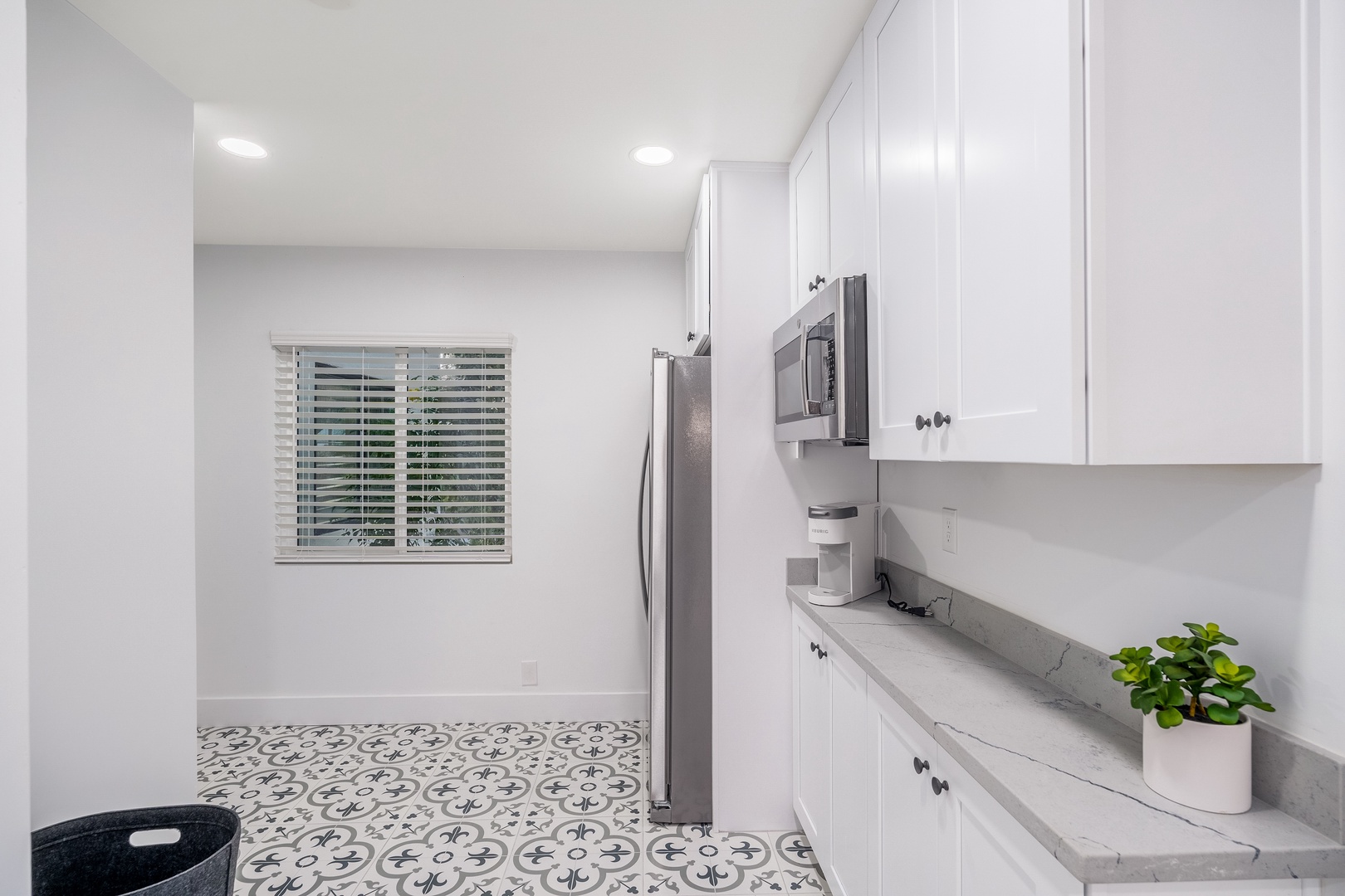 Step into your bright, spotless kitchen with modern stainless steel appliances, sleek white cabinetry, and stylish patterned tile underfoot—ready for your morning coffee or a home-cooked meal.