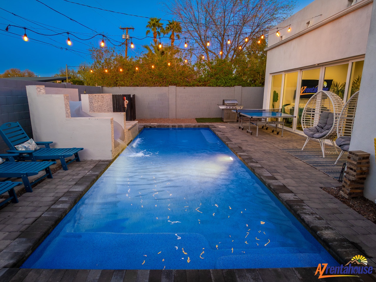 Private oasis with illuminated pool and modern patio for evening relaxation and outdoor dining.