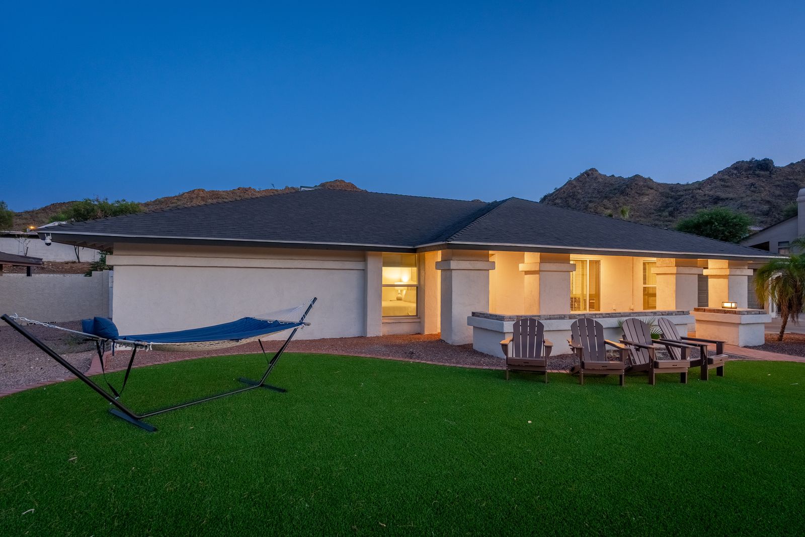 Modern single-level home nestled against rugged desert hills, with spacious lawn and parking, perfect for groups seeking southwestern tranquility.