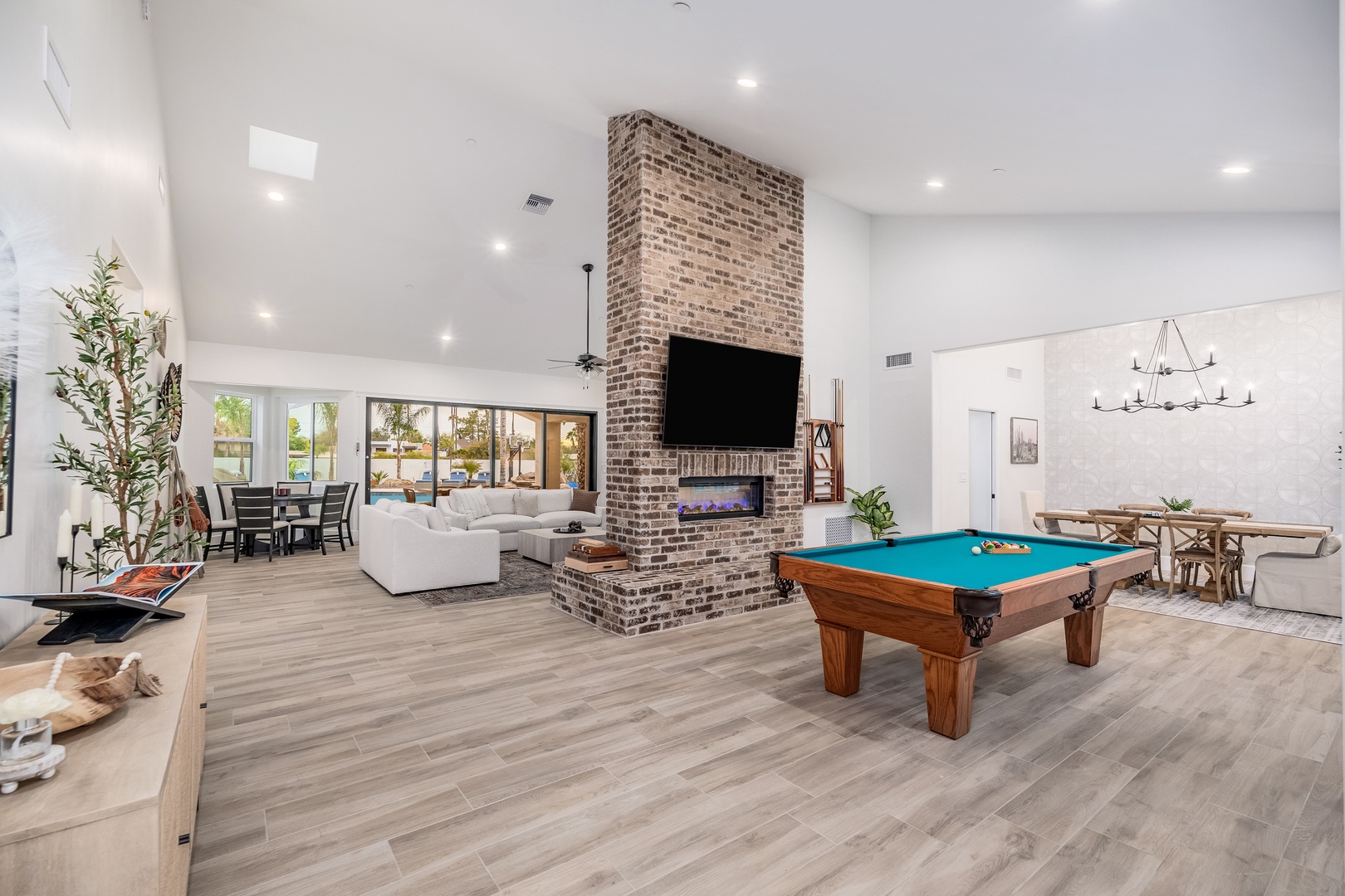 Gather in this stunning open-concept living space where soaring ceilings and warm brick fireplace create the perfect backdrop for your vacation memories. Challenge friends to pool while enjoying modern comfort and natural light streaming through expansive