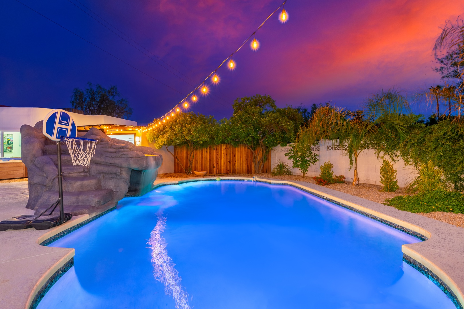 Picture yourself unwinding in this glowing private pool at dusk, surrounded by lush greenery and warm string lights, perfect for evening swims or poolside relaxation.