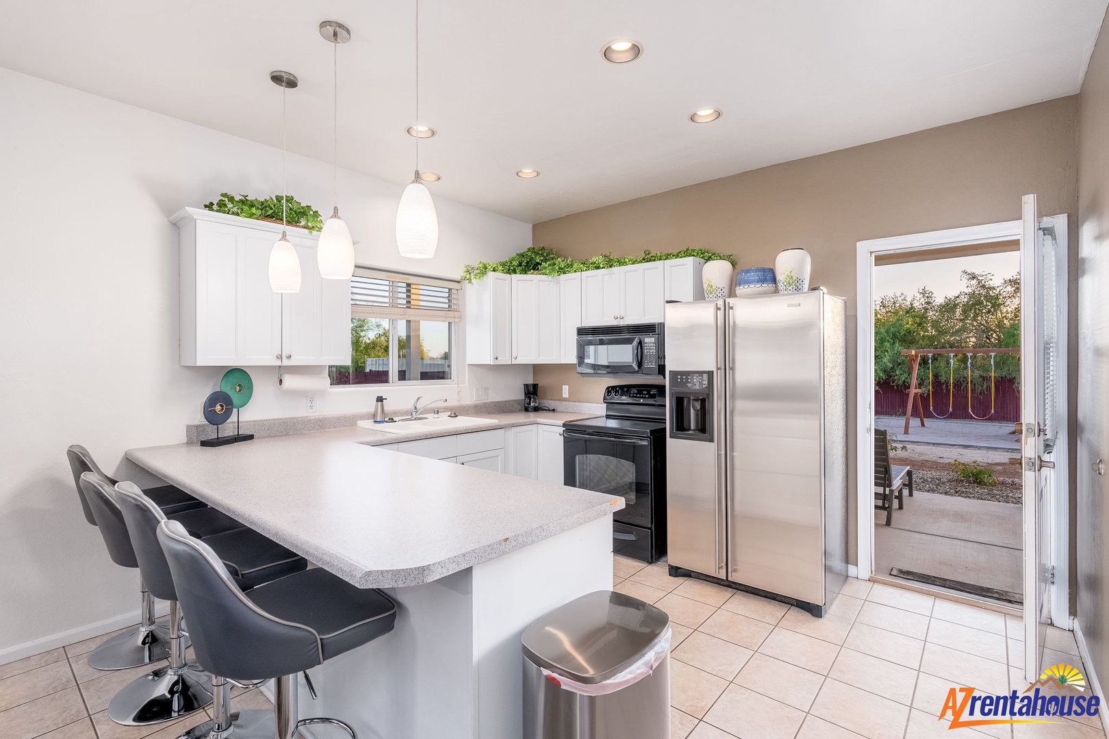 Your fully equipped kitchen features stainless steel appliances, a spacious breakfast bar with modern seating, and easy access to your private backyard oasis.