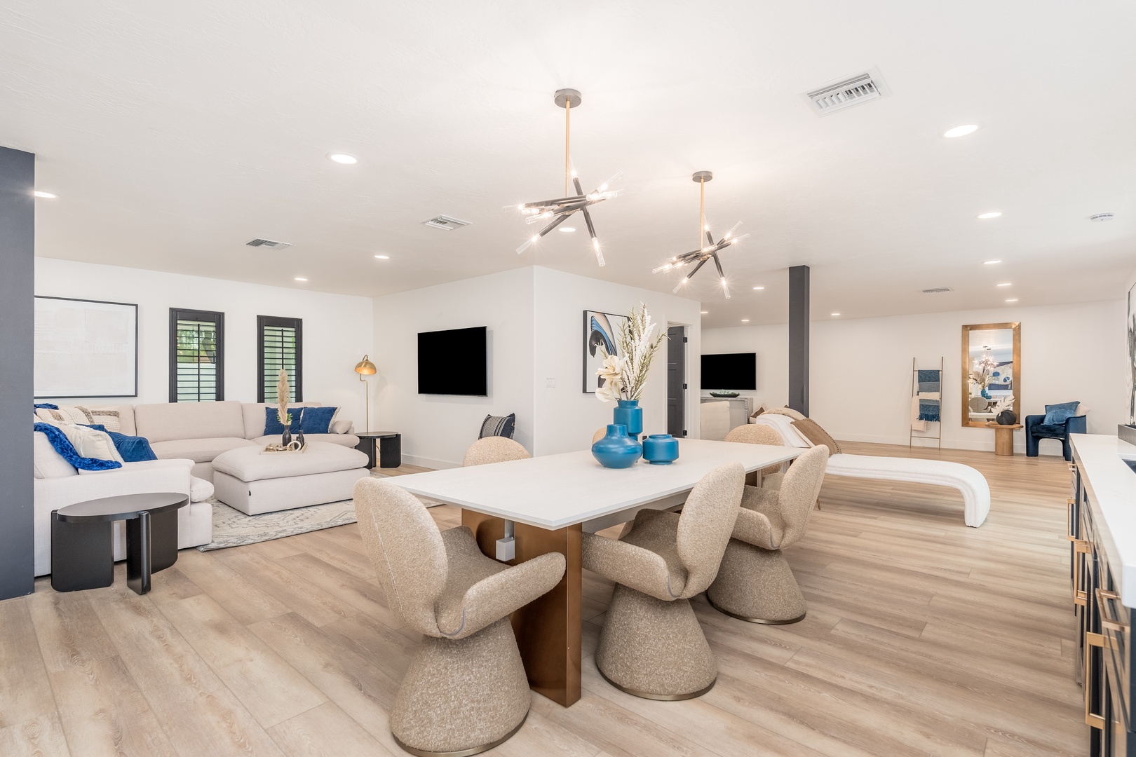 Gather around the spacious dining table or unwind on plush seating in your open-concept living area, where modern design meets relaxed comfort under stylish statement lighting.