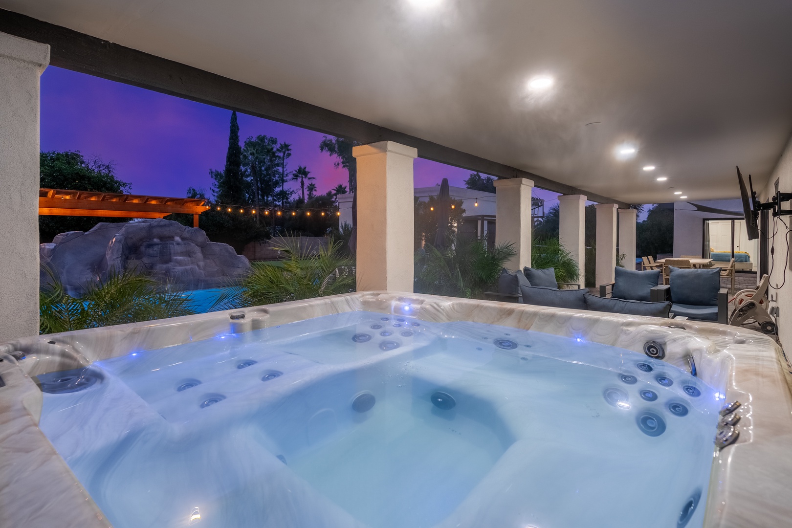 Sink into your private hot tub as twilight paints the sky, with resort-style pool views and a dreamy outdoor lounge just steps away—pure evening bliss.