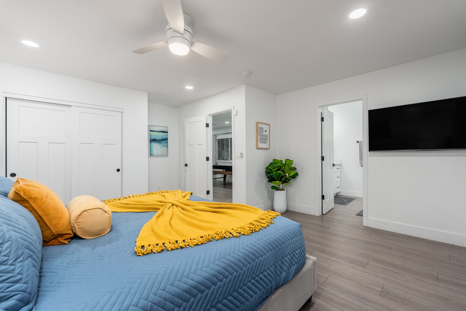 Your bright, modern bedroom features a ceiling fan overhead, spacious closets, and a sleek flat-screen TV—everything you need for a comfortable stay.