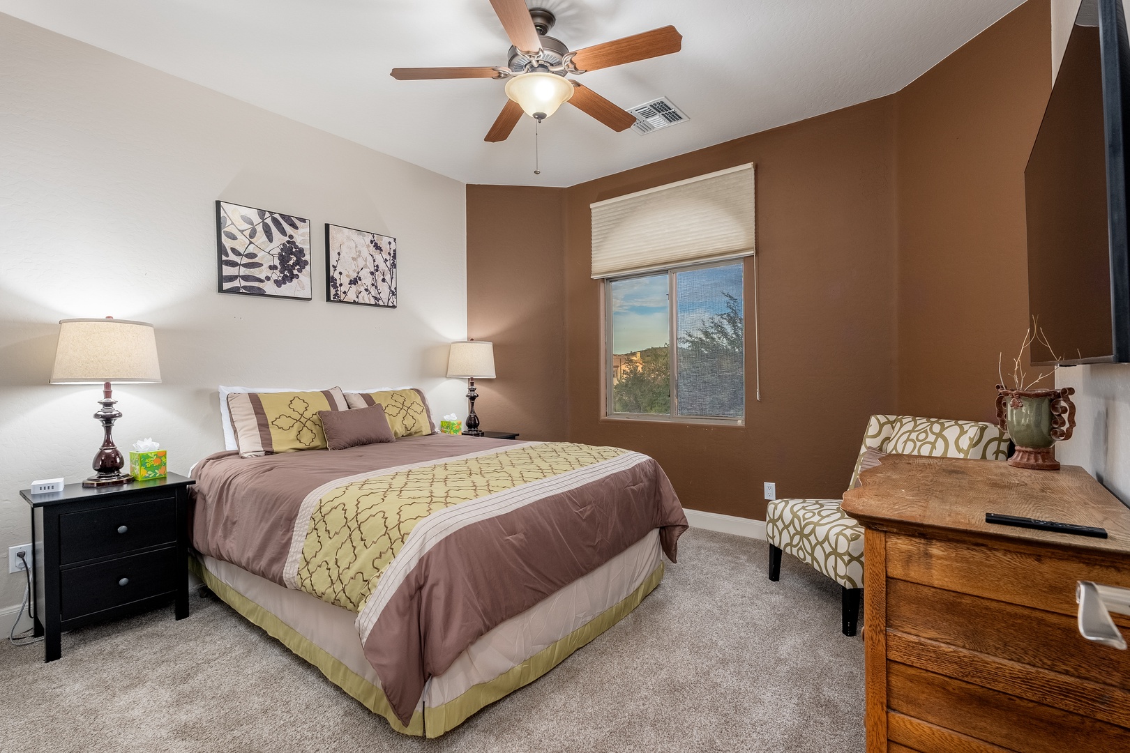 Drift off under a ceiling fan in this cozy bedroom, where warm tones and plush bedding create a peaceful retreat after your desert adventures.