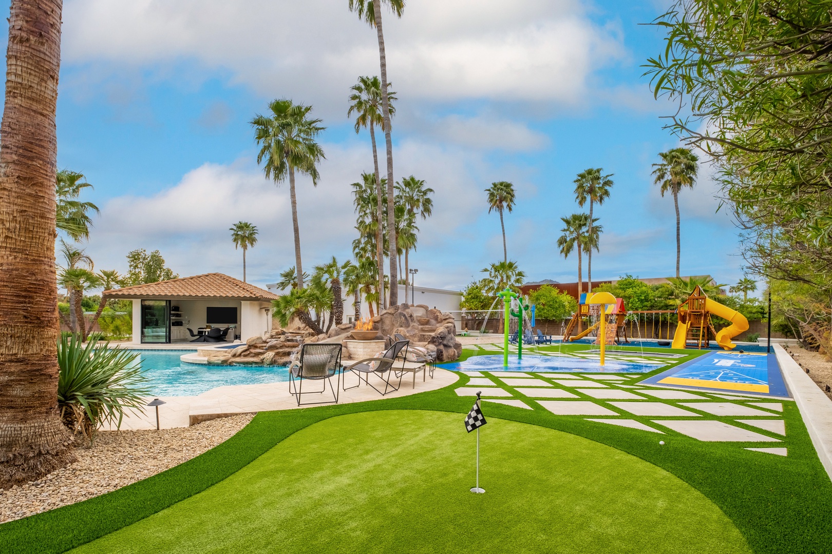 This private backyard paradise features a sparkling pool, waterslide splash zone, and putting green—perfect for family fun under swaying palms.