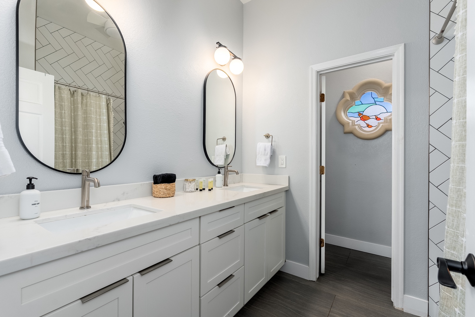 Step into your bright, elegantly designed bathroom featuring dual sinks with spacious countertops, chic mirrors, modern lighting, and herringbone tile accents that blend style and comfort seamlessly.