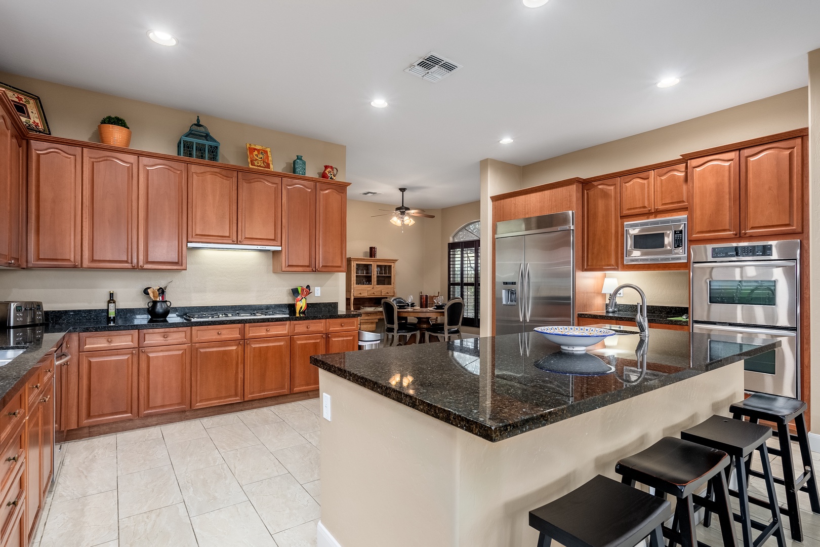 Spacious kitchen with granite countertops, stainless steel appliances, and a generous center island with seating—your culinary home away from home, ready for family meals and vacation cooking.
