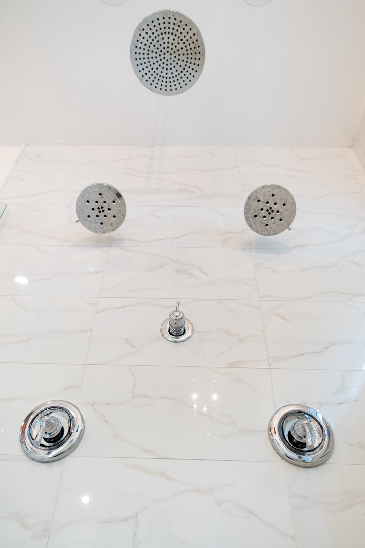 A luxurious multi-head shower system with marble surrounds awaits, featuring dual body jets and an overhead rain shower to envelop you in relaxation.