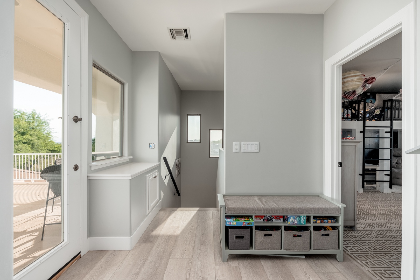 Step into your light-filled entryway with a convenient bench for storing gear and a view of the sunny deck just beyond the glass door.