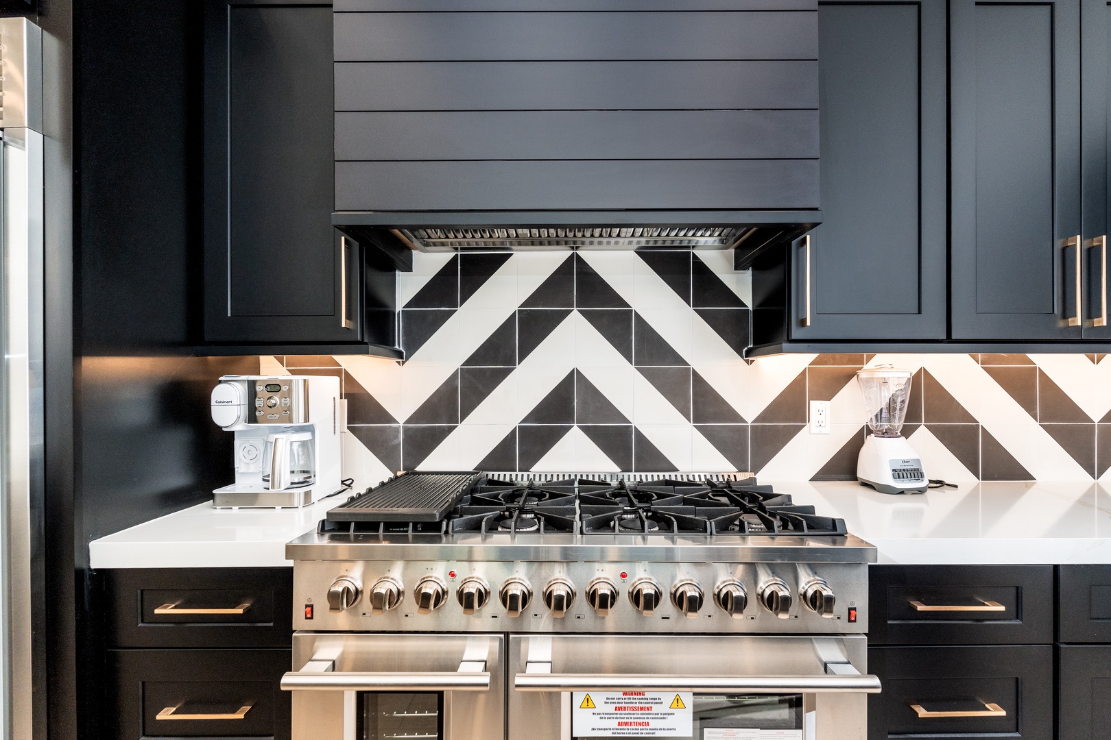 Unleash your inner chef with a pro-grade gas range, bold geometric backsplash, and sleek dark cabinetry. Your culinary adventures start here.