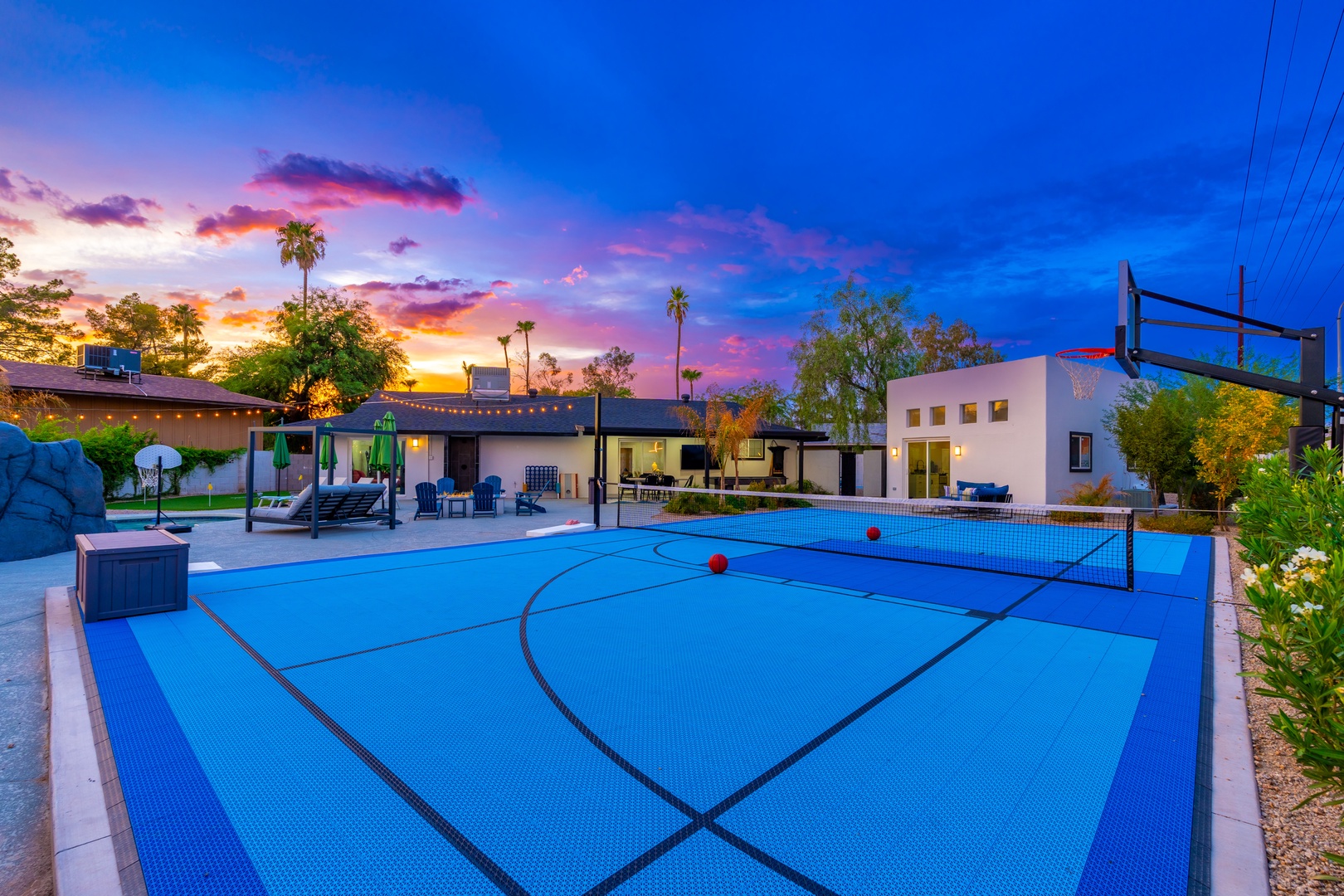 Stunning sunset colors frame the property's multi-sport court and pool area, creating a vibrant backdrop for outdoor recreation and relaxation at this desert retreat.