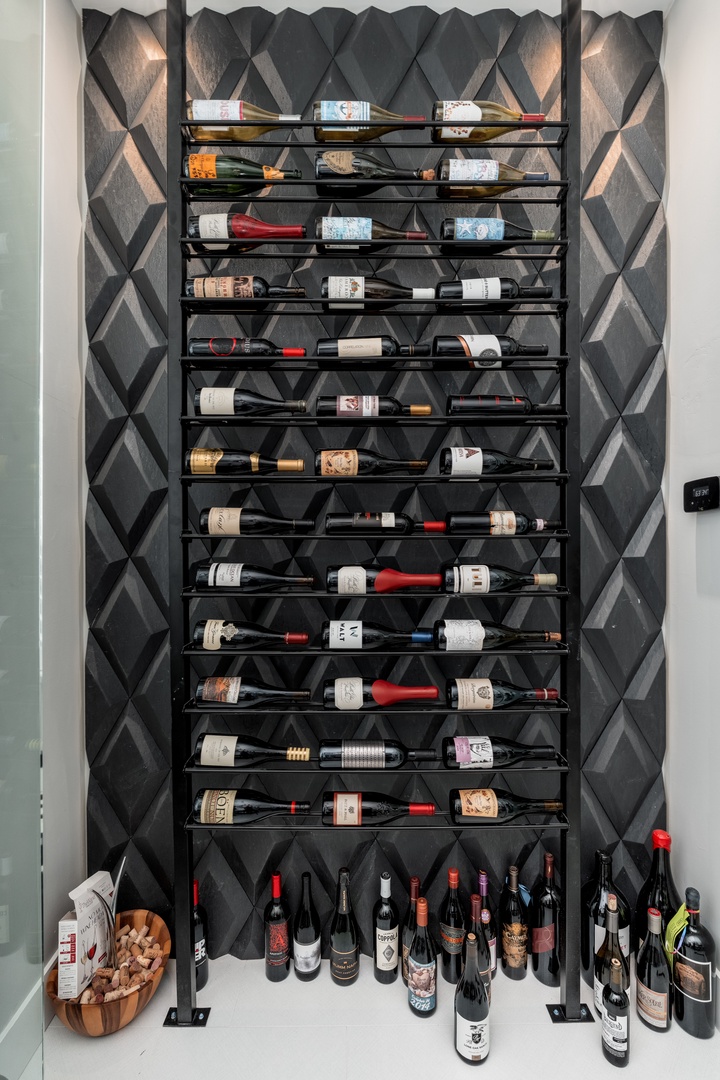 An impressive floor-to-ceiling wine rack showcases an extensive collection against a striking geometric backdrop, offering you a curated selection for every occasion.