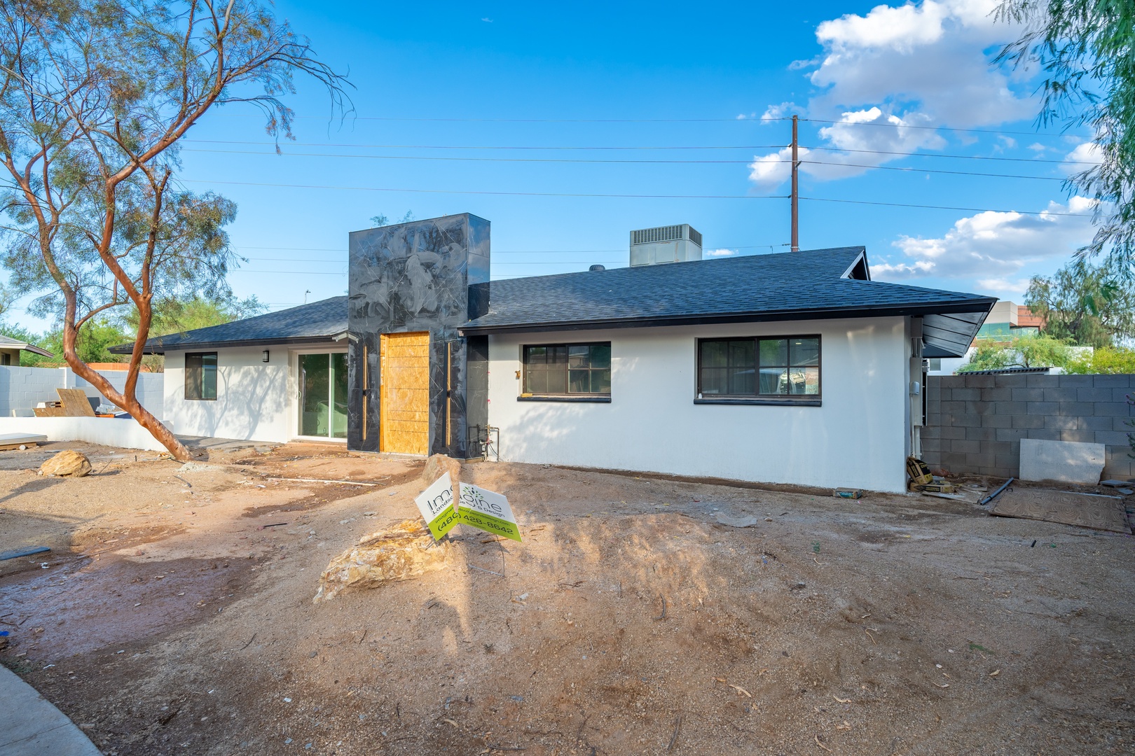 Modern single-story rental home with clean white exterior, dark roof, and desert landscaping, located in a quiet residential neighborhood with mountain views.