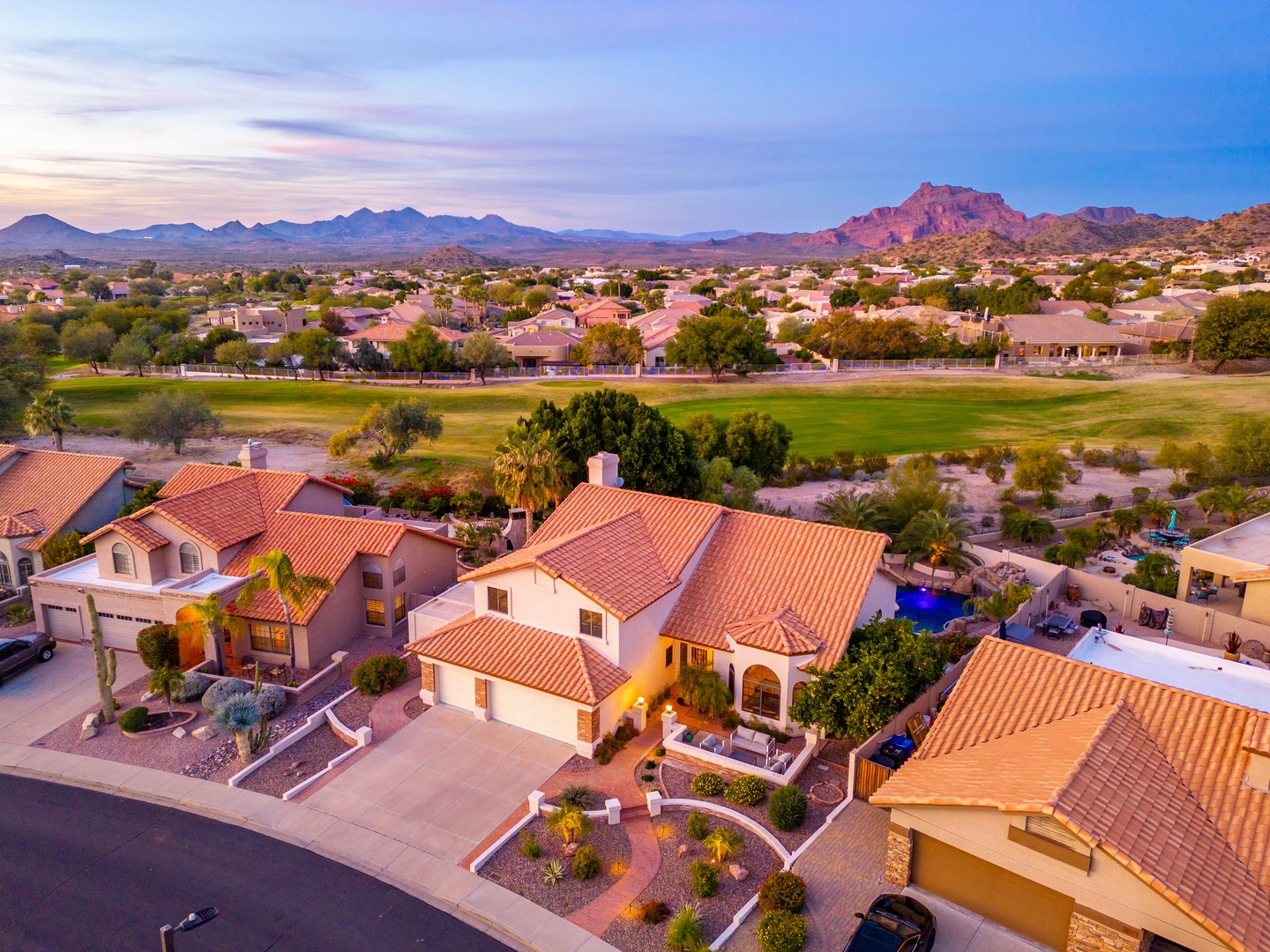Aerial view of the property nestled in a scenic desert community, with dramatic mountain ranges and a nearby golf course highlighting the area's natural beauty and leisure appeal.