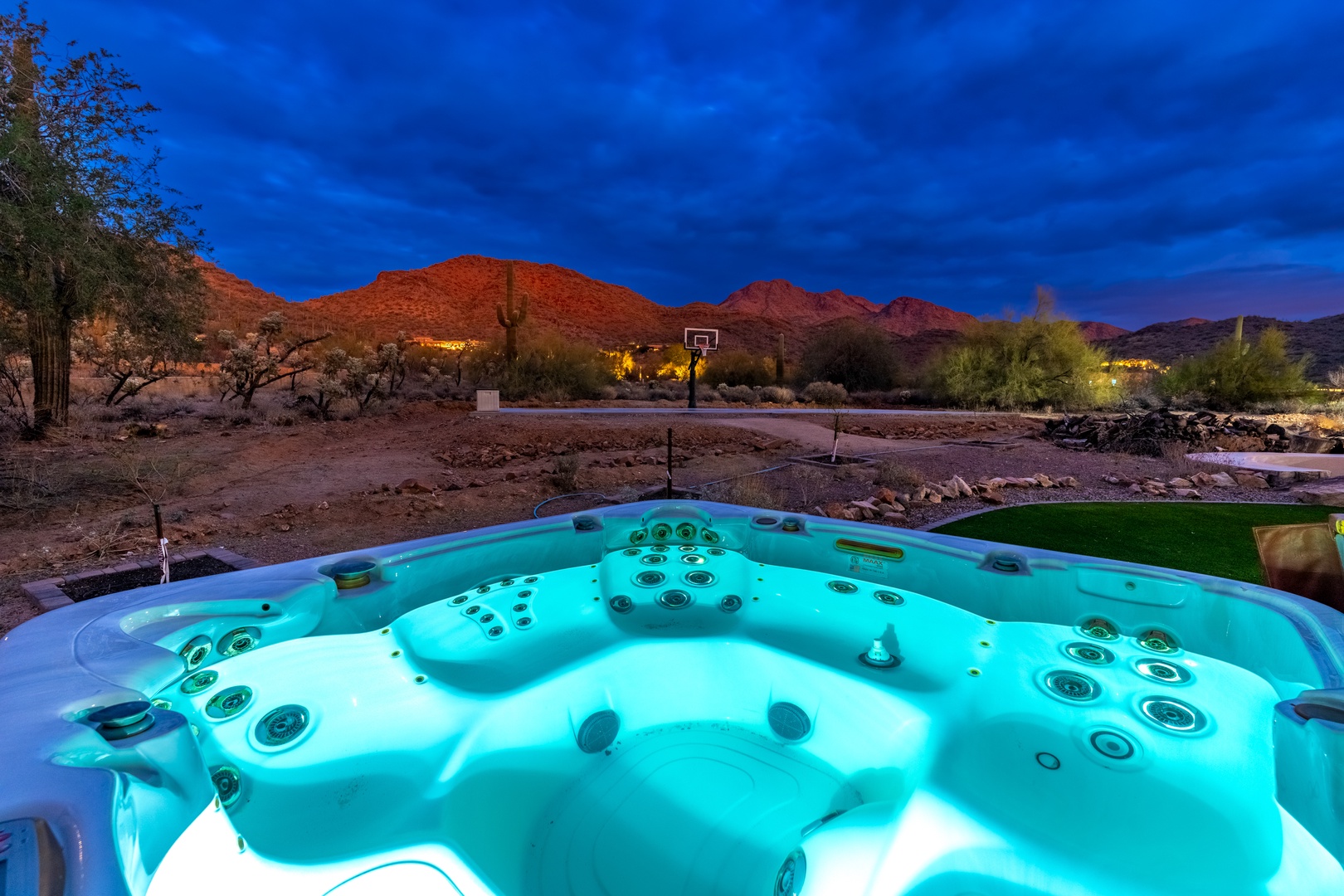 Soak in the hot tub as twilight paints desert mountains brilliant orange, with dramatic skies and desert landscape stretching before you—pure southwest magic.