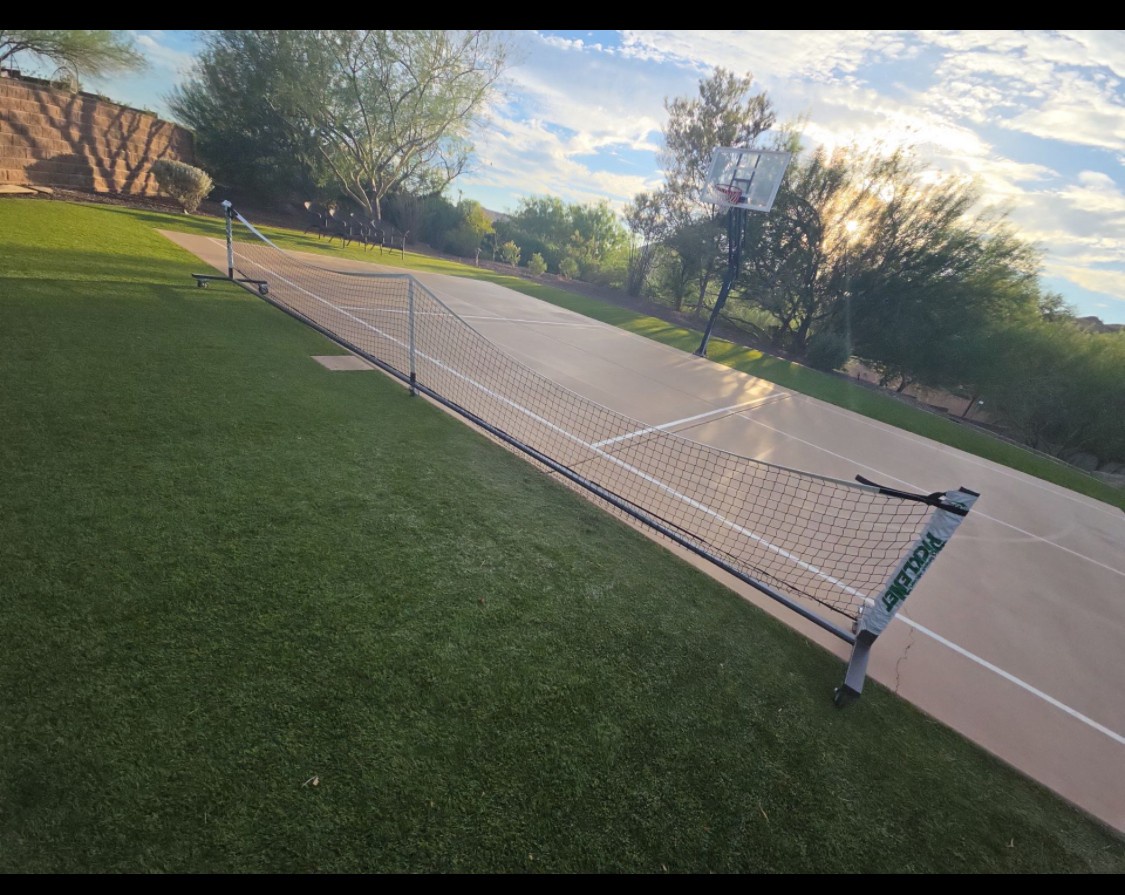 The property features outdoor sports facilities including a tennis court and basketball hoop set within landscaped grounds with mature trees and open green spaces.