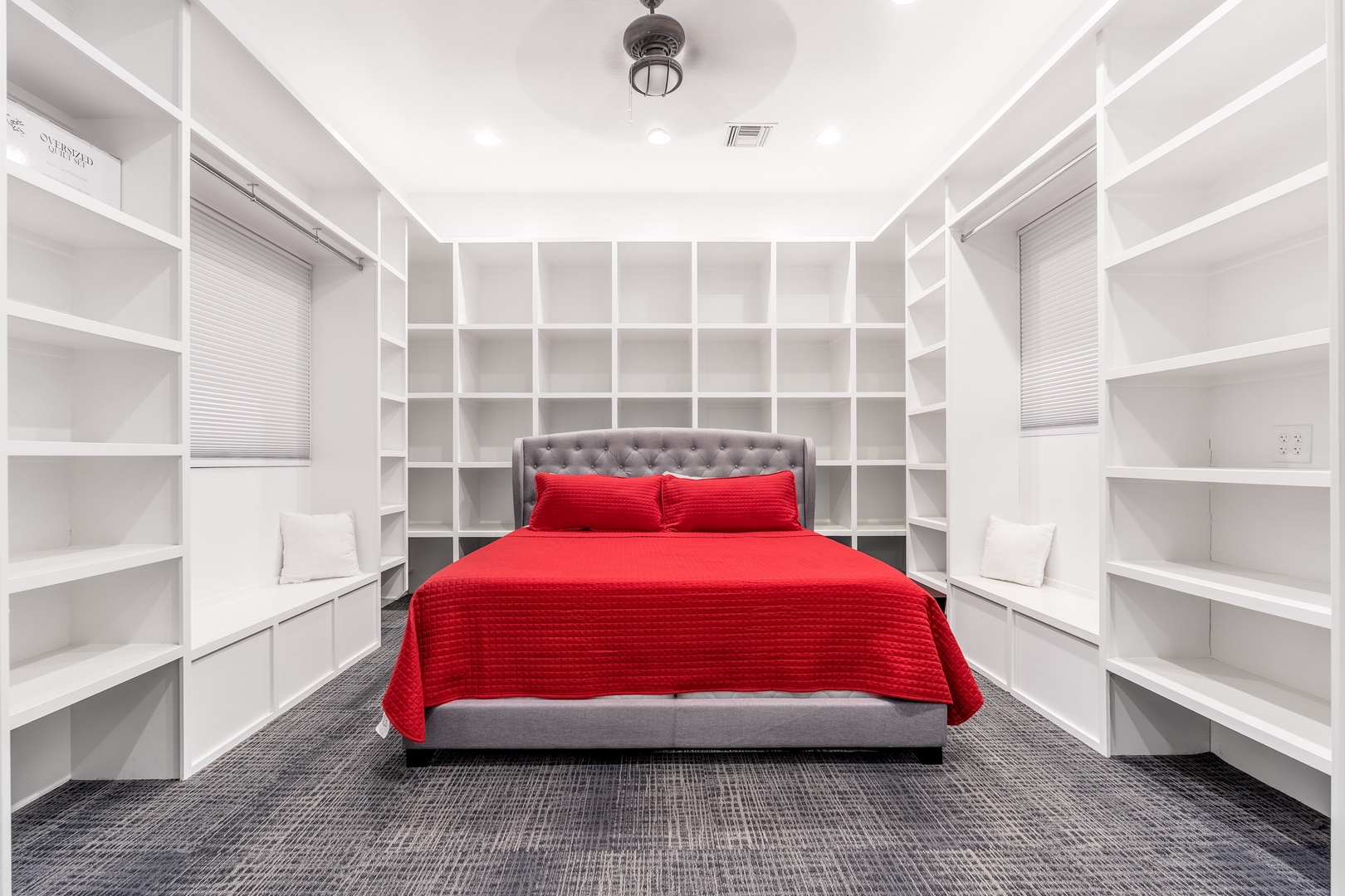Unwind in your cozy bedroom with its striking red bedding and floor-to-ceiling storage shelves—perfect for organizing your belongings and settling in comfortably.