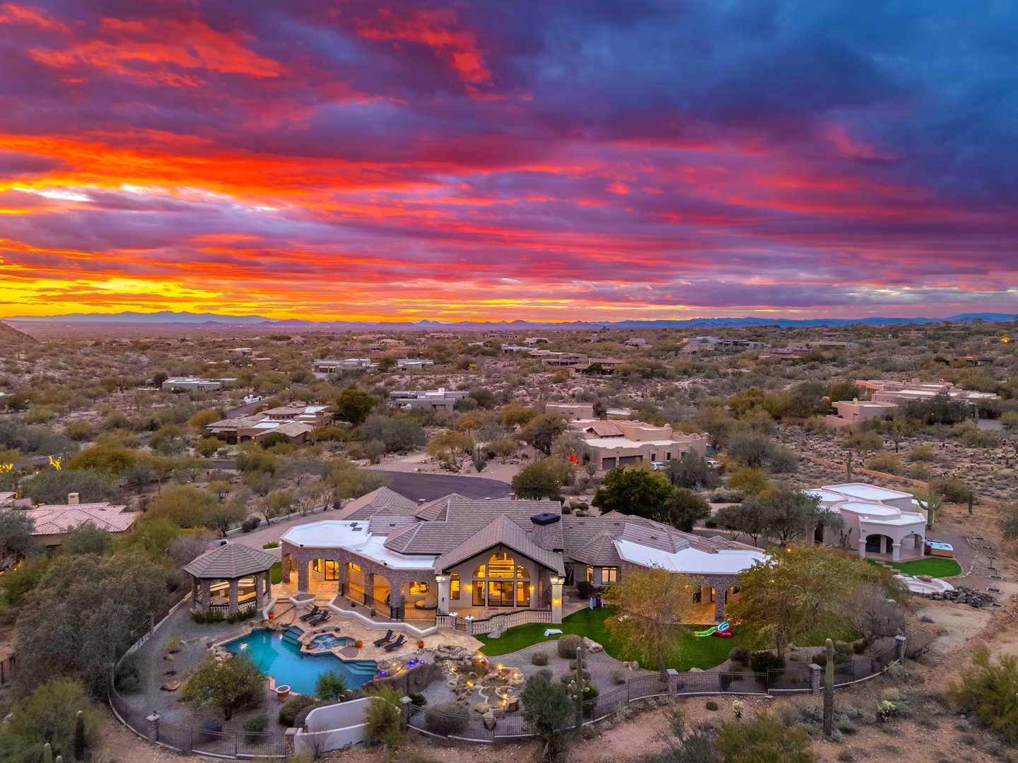 Spectacular desert sunset illuminates the property and surrounding Sonoran landscape with vibrant crimson and golden hues stretching across mountain ranges.