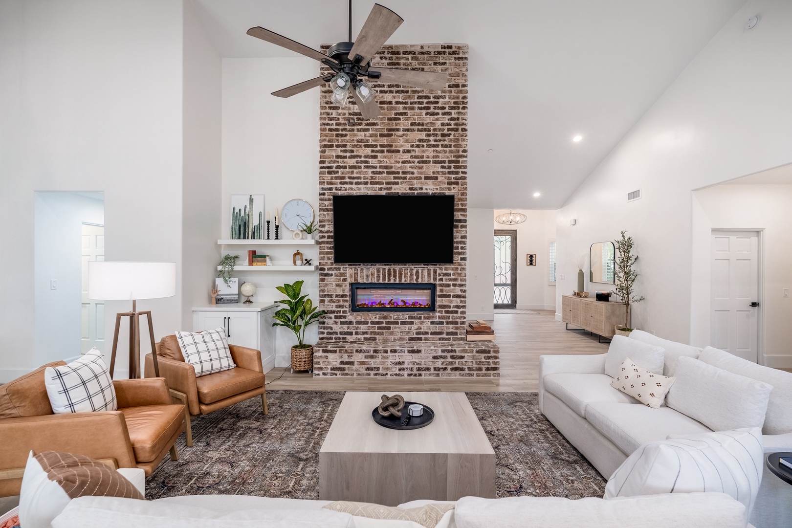Sink into plush seating and unwind in your open, light-filled living room featuring a cozy fireplace and soaring ceilings that create an instantly welcoming retreat.