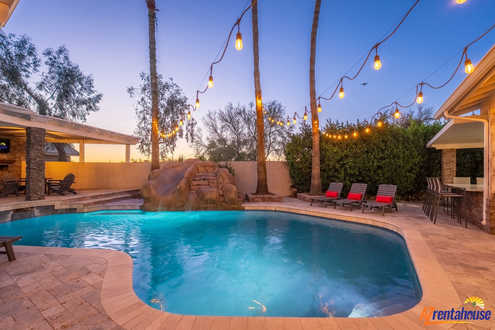 Sparkling pool under string lights at dusk creates a magical desert oasis perfect for evening swims and starlit gatherings in this private backyard retreat.