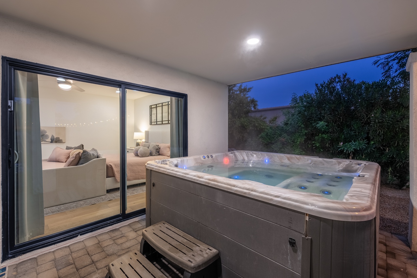Step outside your private suite to unwind in the bubbling hot tub beneath the evening sky, where soft lighting and lush greenery create your own peaceful retreat.
