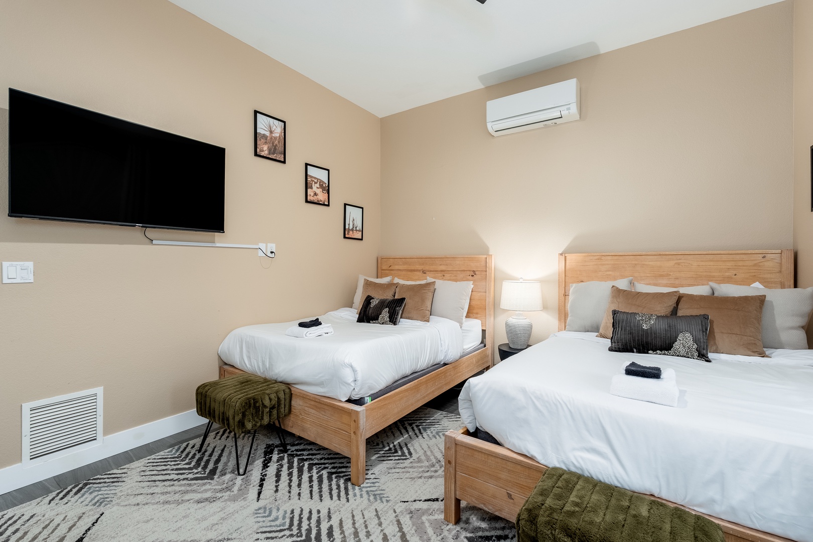 Unwind in this bright, spacious bedroom featuring two plush beds with crisp linens, a large flat-screen TV for your entertainment, and climate-controlled comfort with modern air conditioning.